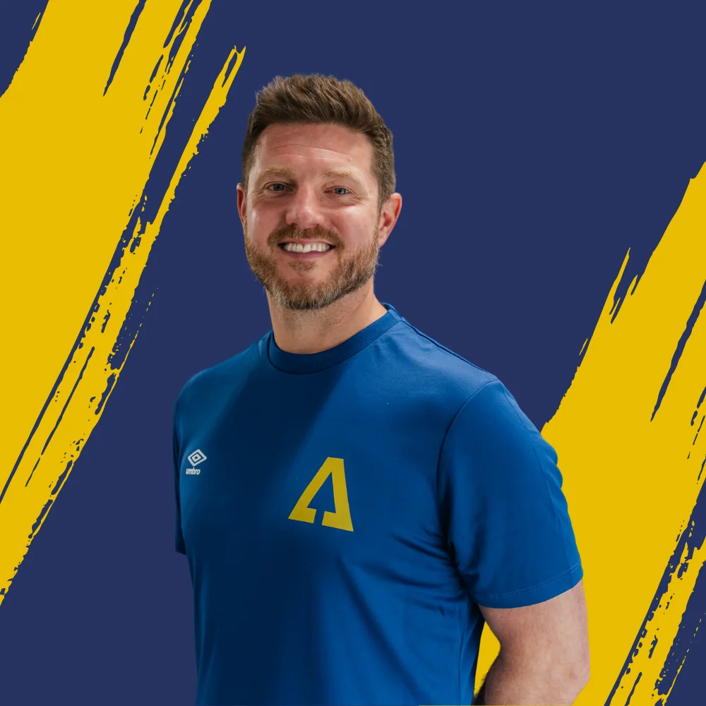 Dave Hunt smiling in a blue Ascension T-shirt in front of a navy and gold backdrop
