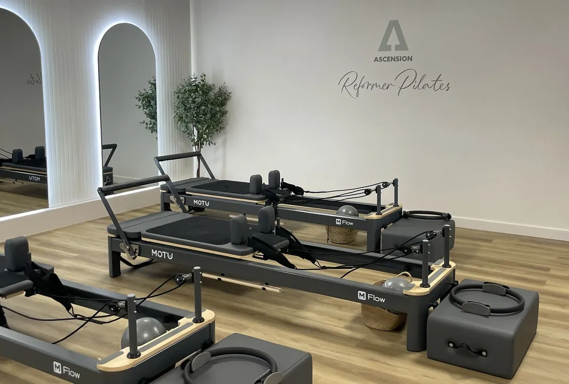 Angled view of the Ascension Reformer Pilates studio, reformer beds beside the branded feature wall