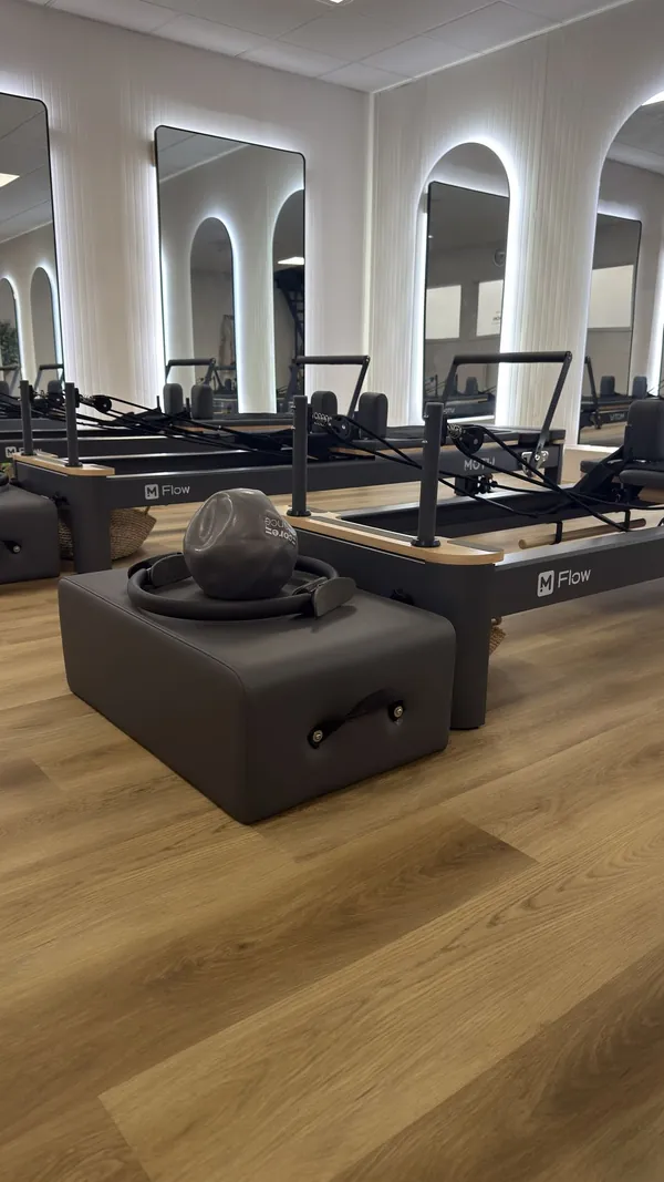 Reformer bed with Pilates ring and weighted ball, studio floor and mirrors in the background