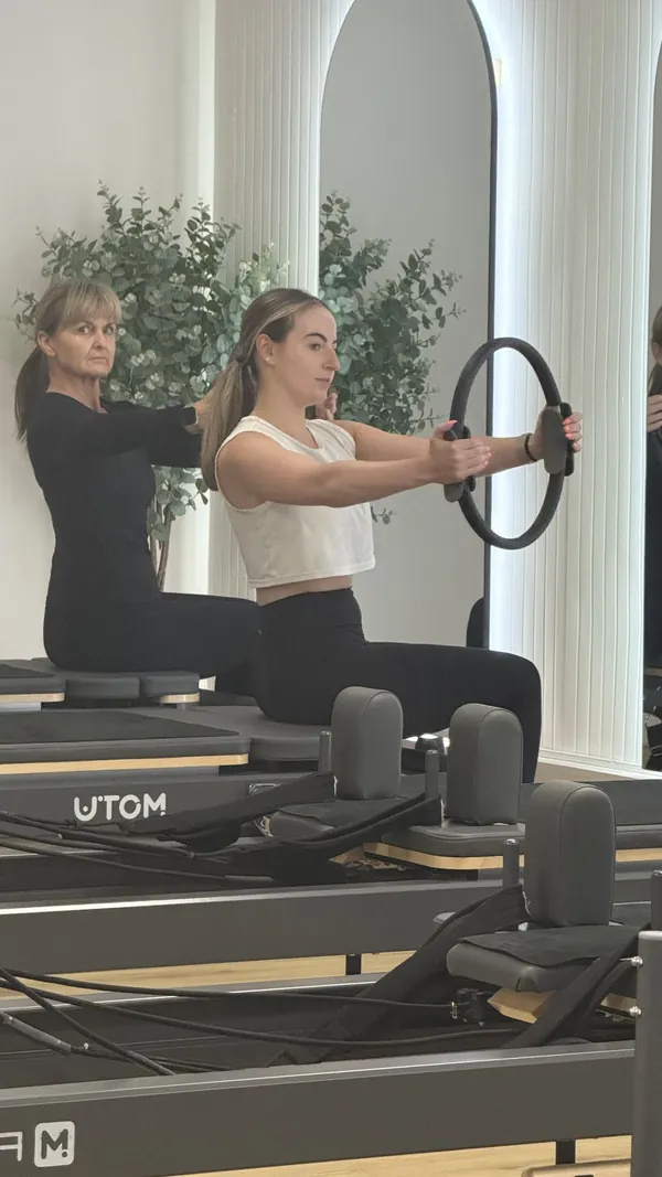 Two clients on reformer beds during a group session