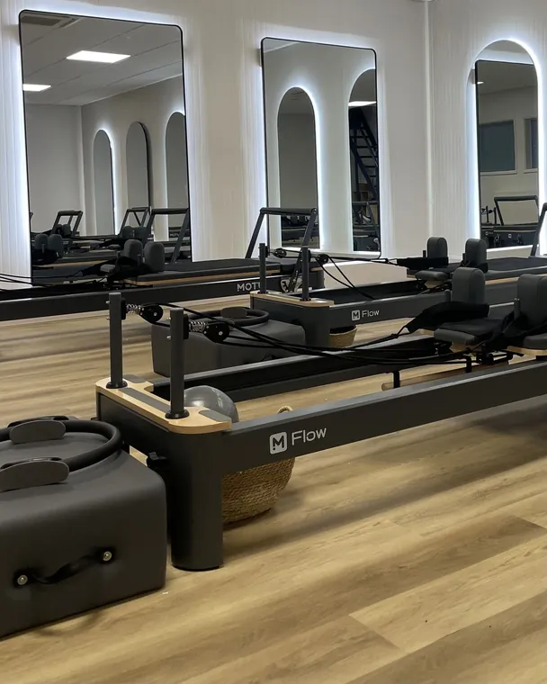 Reformer Pilates studio at Ascension, rows of reformer beds beneath arched, backlit mirrors