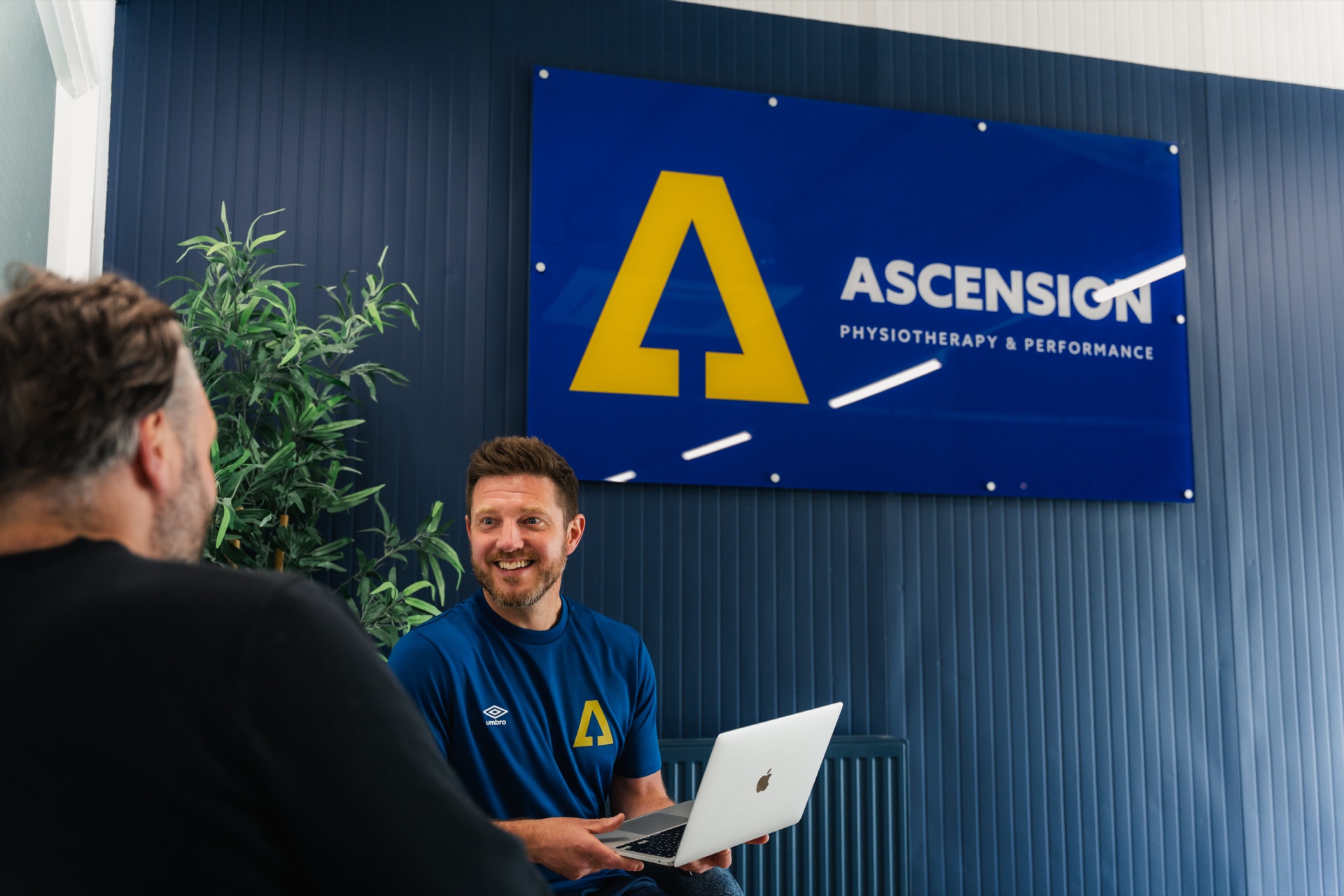 Ascension coach talking through a client's training plan on a laptop in the gym