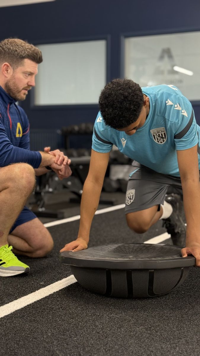 Young footballer working on a balance exercise with an Ascension coach